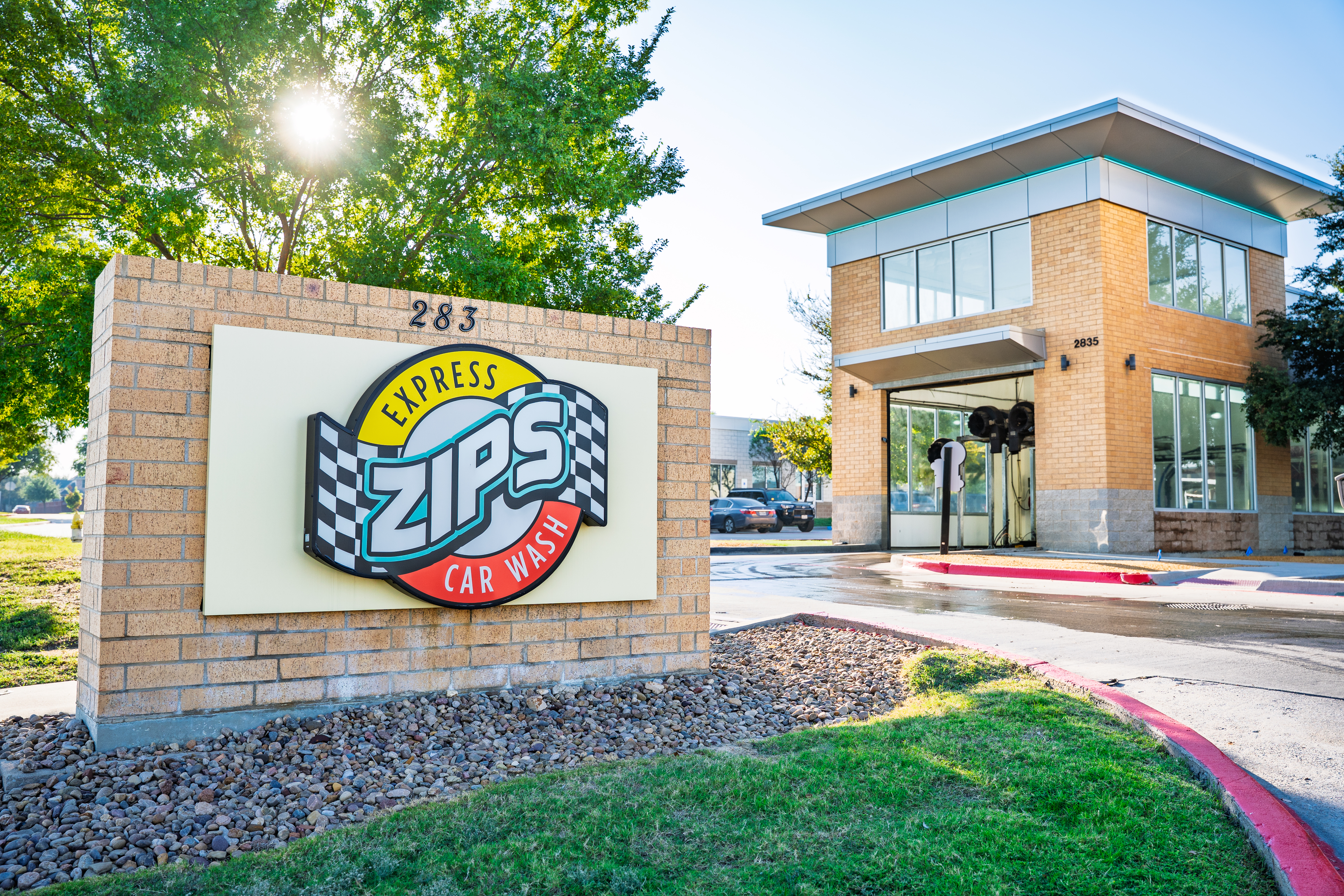 Exterior end of tunnel and sign for ZIPS Car Wash with logo