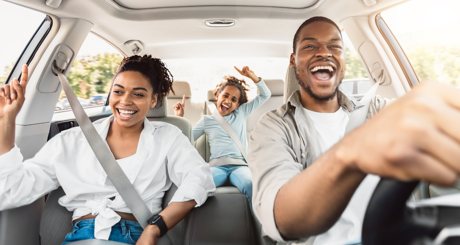 A Black man, woman, and child smile and have fun while driving home from the car wash