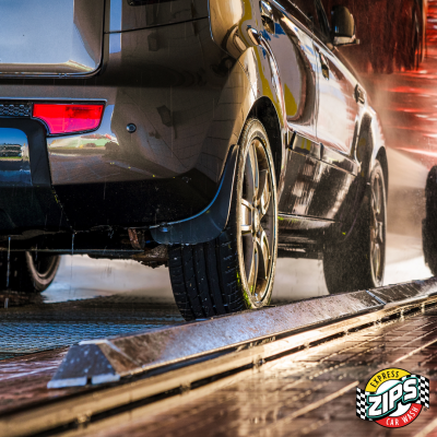 Car being washed in tunnel, focusing on the wheels going through with a ZIPS Car Wash logo in the lower-right corner