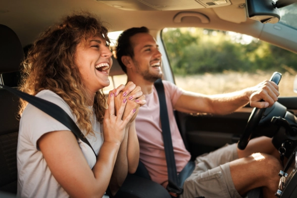 Man and woman smiling in a car as they drive